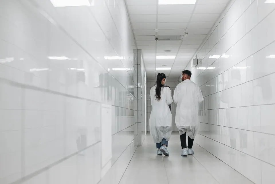 Klinik koridorunda yürüyen iki sağlık çalışanı